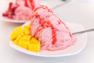 Strawberry ice cream with mango in white dish on table