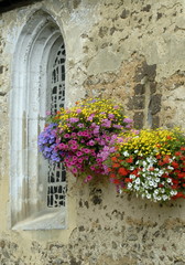 Massifs de fleurs sur le mur de l'église d'un village de Normandie, France
