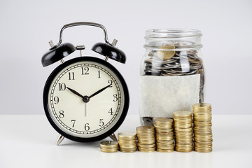 Alarm clock and coins on a white surface