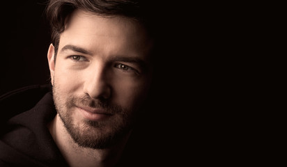 young man close up portrait, on black background