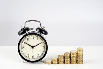 Alarm clock and coins on a white surface