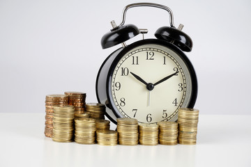 Alarm clock and coins on a white surface