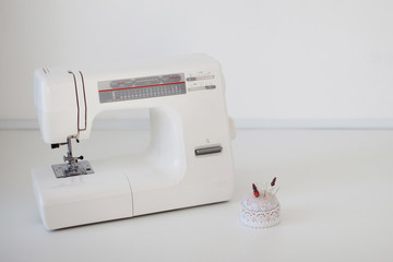 White sewing machine, tailoring tape, needle bar on table in workshop