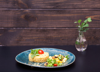 Juicy bulgur with vegetables on black and wooden backgrounds