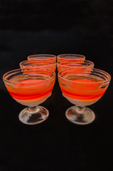 sweet delicious dessert of multi-colored jelly in a glassware isolated on a black background