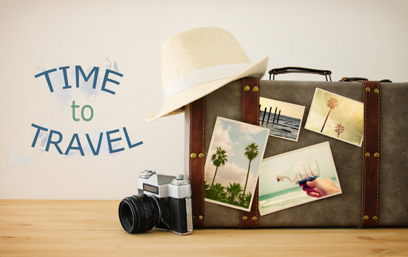 Image of old vintage luggage with vacation photos over wooden floor.