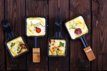 Fototapeten Delicious traditional Swiss melted raclette cheese on diced boiled or baked potato. © beats_