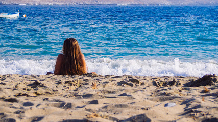 Amorgos, Greece-August 2,2017.A girl enjoying the sun and the sea on the beach of Psili Ammos.