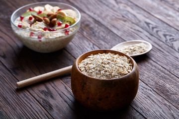 Diet breakfast oatmeal with fruits, bowl and spoon with oat flakes, selective focus, close-up