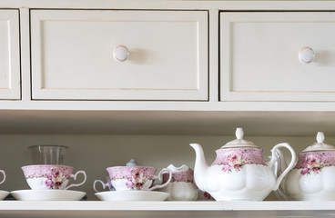Fototapeta na wymiar vintage English tea set with pink floral pattern on a white cupboard