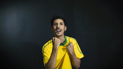 Male athlete or fan in yellow uniform celebrating on black background