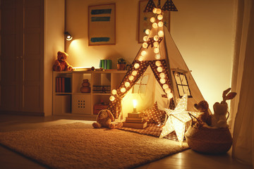 interior of children's playroom with tent, lamps and toys in dark. © JenkoAtaman