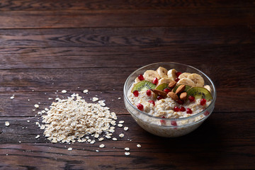 Diet breakfast oatmeal with fruits, bowl and spoon with oat flakes, selective focus, close-up