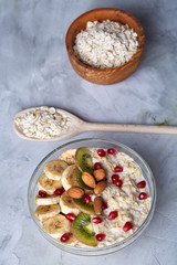 Diet breakfast oatmeal with fruits, bowl and spoon with oat flakes, selective focus, close-up
