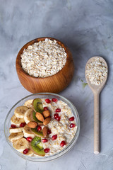 Diet breakfast oatmeal with fruits, bowl and spoon with oat flakes, selective focus, close-up