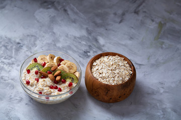 Diet breakfast oatmeal with fruits, bowl and spoon with oat flakes, selective focus, close-up
