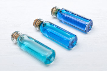Blue essential oil tincture bottles of different transparency on white wooden background. Alternative medicine. Herbal medicine. Aroma therapy.
