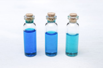 Blue essential oil tincture bottles of different transparency on white wooden background. Alternative medicine. Herbal medicine. Aroma therapy.