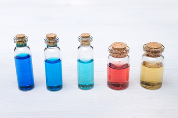 Set of colorful essential oil tinctures on white wooden table background. Alternative medicine.