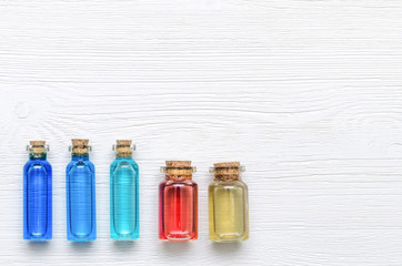 Set of colorful essential oil tinctures on white wooden table background with copy space, top view. Alternative medicine.