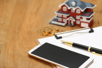 house model,calculator,pen,and coins on wooden table