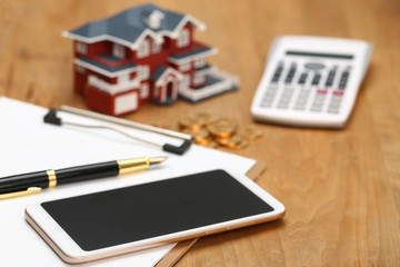 house model,calculator,pen,and coins on wooden table