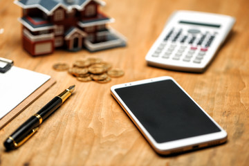 house model,calculator,pen,and coins on wooden table