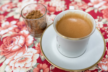 espresso shot in vintage english cup on rose pattern table cloth