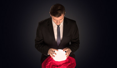 Handsome businessman with magic ball and copy space and dark background
