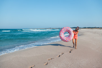 Girl with donut lilo on the beach