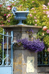 portail bleu, vasque et  massif de fleurs mauves, France
