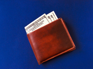 Brown leather wallet with four hundred dollars on blue board