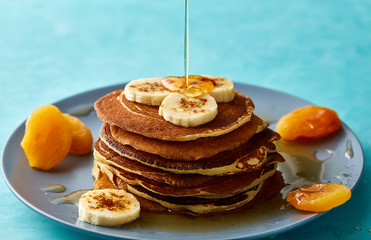 Pile of homemade pancakes with honey and walnuts on rustic wooden background, selective focus