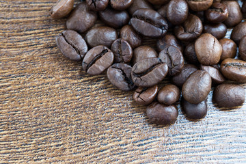 Coffee beans on a dark background and a wooden table. Closeup.