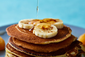 Pile of homemade pancakes with honey and walnuts on rustic wooden background, selective focus