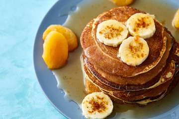 Pile of homemade pancakes with honey and walnuts on rustic wooden background, selective focus