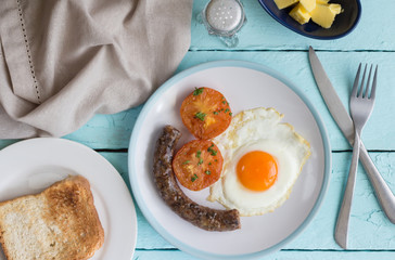 Breakfast dish with fried egg, traditional South African sausage, tomato and toast. Overhead view