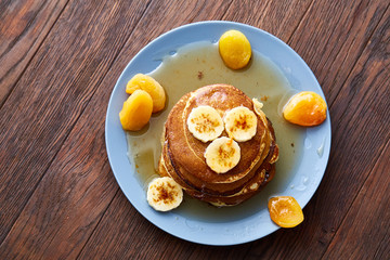 Pile of homemade pancakes with honey and walnuts on rustic wooden background, selective focus