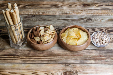 Snacks for beer on a wooden table. Chips, croutons, bread sticks and pistachios