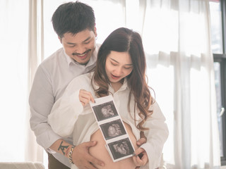 Pregnant couple looking at an ultrasound at home