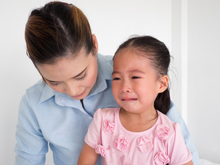 Young mother holding her crying baby girl;