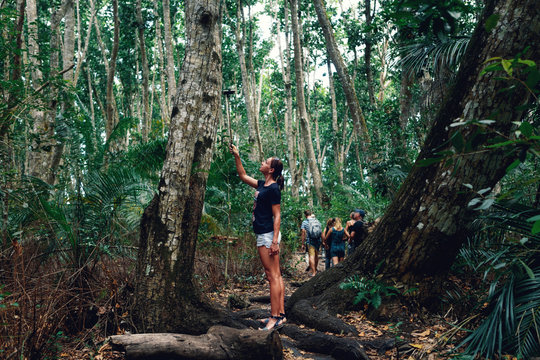 Woman tourist photographing herself in dense tropical forest