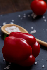Vegetarian still life with fresh grape tomatoes, pepper and salt in wooden spoon on wooden background, selective focus