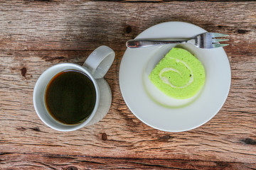 Green Jam Roll Cake with back coffee on Wooden Table	