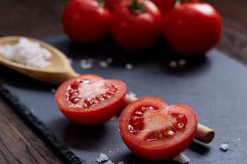 Vegetarian still life with fresh grape tomatoes, pepper and salt in wooden spoon on wooden background, selective focus