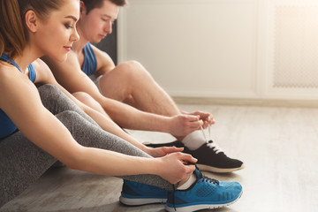 Couple tying up laces on sport shoes closeup
