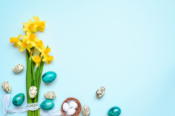 Easter Background with easter eggs and spring flowers on blue background. top view