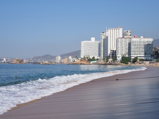 Beauty panorama of sandy beach at bay of ACAPULCO city in Mexico with white hotels buildings and waves of Pacific Ocean