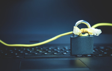 Yellow network cable with a padlock on the laptop. Web security concept
