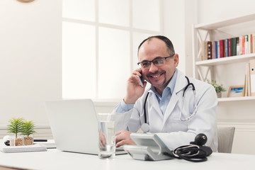 Happy doctor talking on phone with his patient